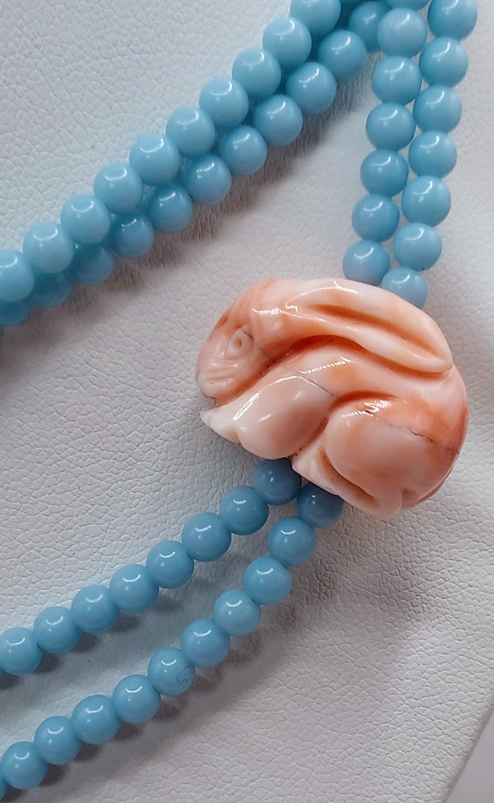 Angel Skin Coral 30-Inch Blue Bead Necklace, on cord with brass lock novelty clasp and pink carved coral bunny charm